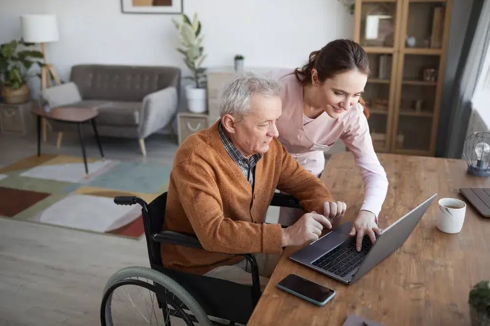 Elderly man in wheelchair with female carer