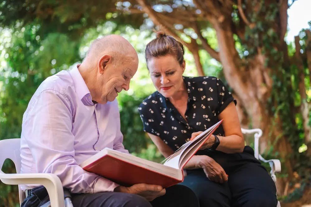 Older man and female carer reading a book together
