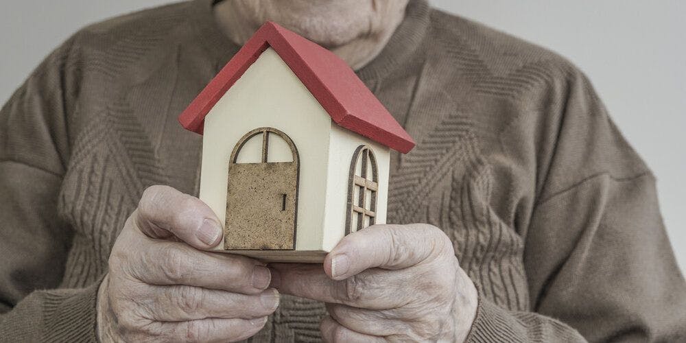 An old person holding a house
